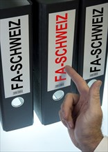 Hand pointing to file folders labeled 'FA-Schweiz'