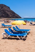Sun beds and a parasol on the sandy beach of Playa de las Teresitas