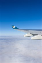 Wing of an Oman Air airplane above the clouds
