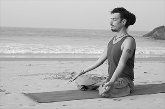 Man meditating on the beach