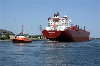 A cargo ship is towed from the Gdansk shipyard by a tug boat