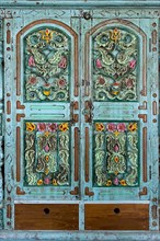 Ornately carved flowers in a turquoise cabinet door