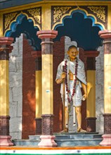 Representation of Mahatma Gandhi with walking stick in a small pavilion on the temple wall