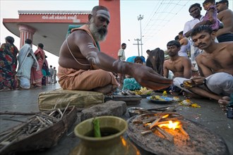 Hindu priest with pilgrims performing a fire ritual at the Ghat Agni Theertham