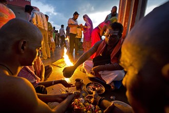 Hindu priest with pilgrims during a fire ritual at the Ghat Agni Theertham