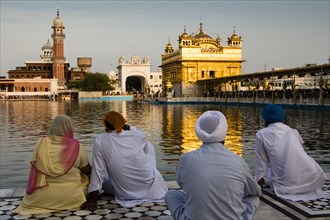 Sikh pilgrims sitting in front of the Harmandir Sahib or Golden Temple