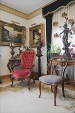 Antique chairs and furnishings adorn a living room inside a Victorian mansion