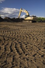 Heavy tire tracks and excavator in a commercial sandpit