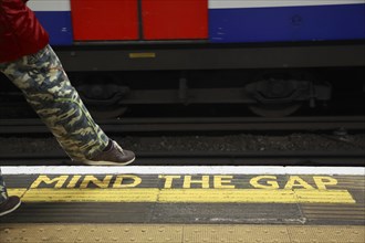 Yellow marking MIND THE GAP on the floor of a station of the London Underground