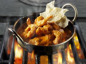 Indian prawn Makhani curry being cooked over hot charcoals