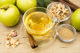 Cup of apple tea with fresh apples and cinnamon sticks