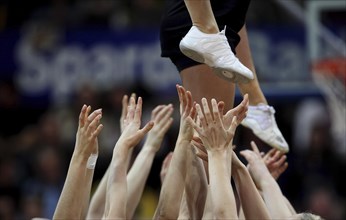 Cheerleaders stretching out their hands to support a cheerleader above