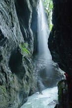 Hiker observing a waterfall in the Partnachklamm gorge