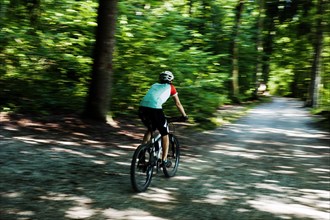 Woman riding a mountain bike along the Forstweg trail in Feldafinger Park
