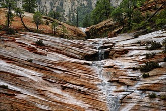 Water draining off over red Navajo sandstone rocks after a rainstorm near Canyon Overlook