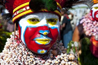 Woman in a colourfully decorated costume with face paint at the traditional sing-sing gathering