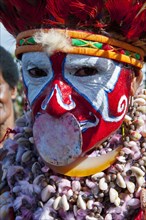 Woman in a colourfully decorated costume with face paint celebrating the traditional sing-sing gathering