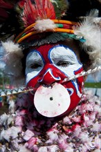 Woman in a colourfully decorated costume with face paint at the traditional sing-sing gathering