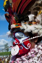 Woman in a colourfully decorated costume with face paint at the traditional sing-sing gathering