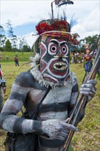 Member of a tribe with colourful decorations and a mask at the traditional sing-sing gathering