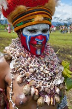 Woman in a colourfully decorated costume with face paint at the traditional sing-sing gathering