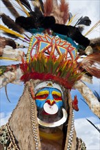 Man in a colourfully decorated costume with face paint at the traditional sing-sing gathering