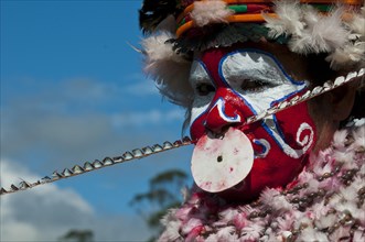 Member of a tribe in a colourfully decorated costume with face paint at the traditional sing-sing gathering