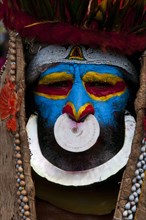 Member of a tribe in a colourfully decorated costume with face paint at the traditional sing-sing gathering