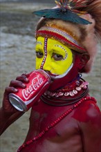 Colourfully decorated and painted boy drinking from a Coke can during the traditional Sing Sing in the highlands