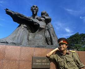 Soldier leaning against the statue of Ho Chi Minh or 'Uncle Ho' with a child