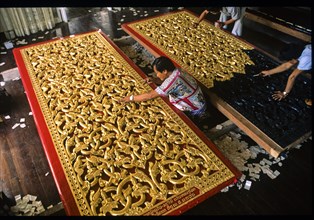 Craftsmen gilding doors with gold leaf