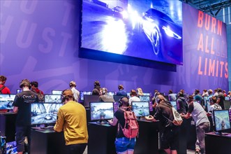 Teenagers at Need for Speed car racing game in front of screens