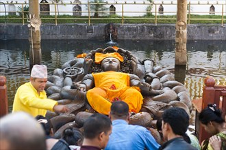 Hindu pilgrims and a brahman at a depiction of Lord Vishnu as Jalashayana Narayan lying in the water