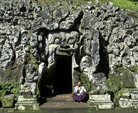 Balinese man sitting at the entrance to the Goa Gajah or Elephant Cave
