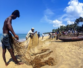 Fishermen repairing a fishing net on the beach