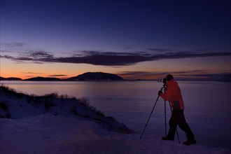 Photographer in front of a fjord at Sunset
