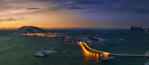 Fjord with an illuminated bridge in winter at sunset