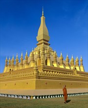 Monk praying in front of Phra That Luang