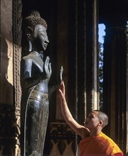 Monk touching a Buddha statue
