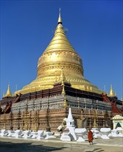 Monk in front of Shwezigon Pagoda with its golden chedi