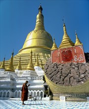 Monk praying in front the Shwemawdaw Paya pagoda