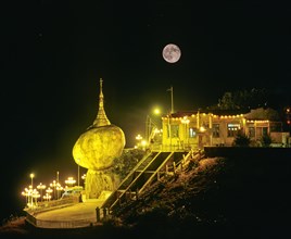 Golden Rock or Kyaiktiyo Pagoda illuminated at night with a full moon
