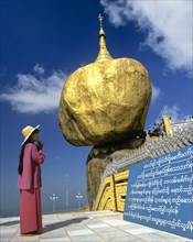 Woman praying in front of the Golden Rock or Kyaiktiyo Pagoda