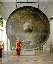 Novice standing in front of a huge bronze gong