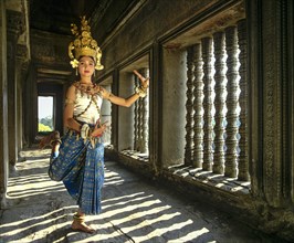 Temple dancer or apsara posing in front of the baluster windows in the temple of Angkor Wat