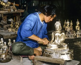 Worker in a silver factory working on a silver Buddha statue