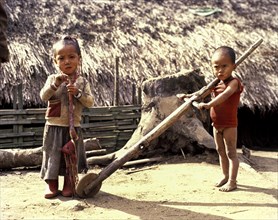 Akha boy and Akha girl in torn clothes with primitive toys