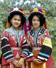 Two Lisu girls wearing colourful headdresses and the traditional costume of the mountain people