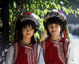 Two Lisu girls wearing colourful headdresses and the traditional costume of the mountain people