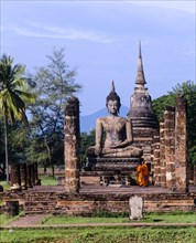Two monks standing in front of the seated Buddha at Wat Mahathat